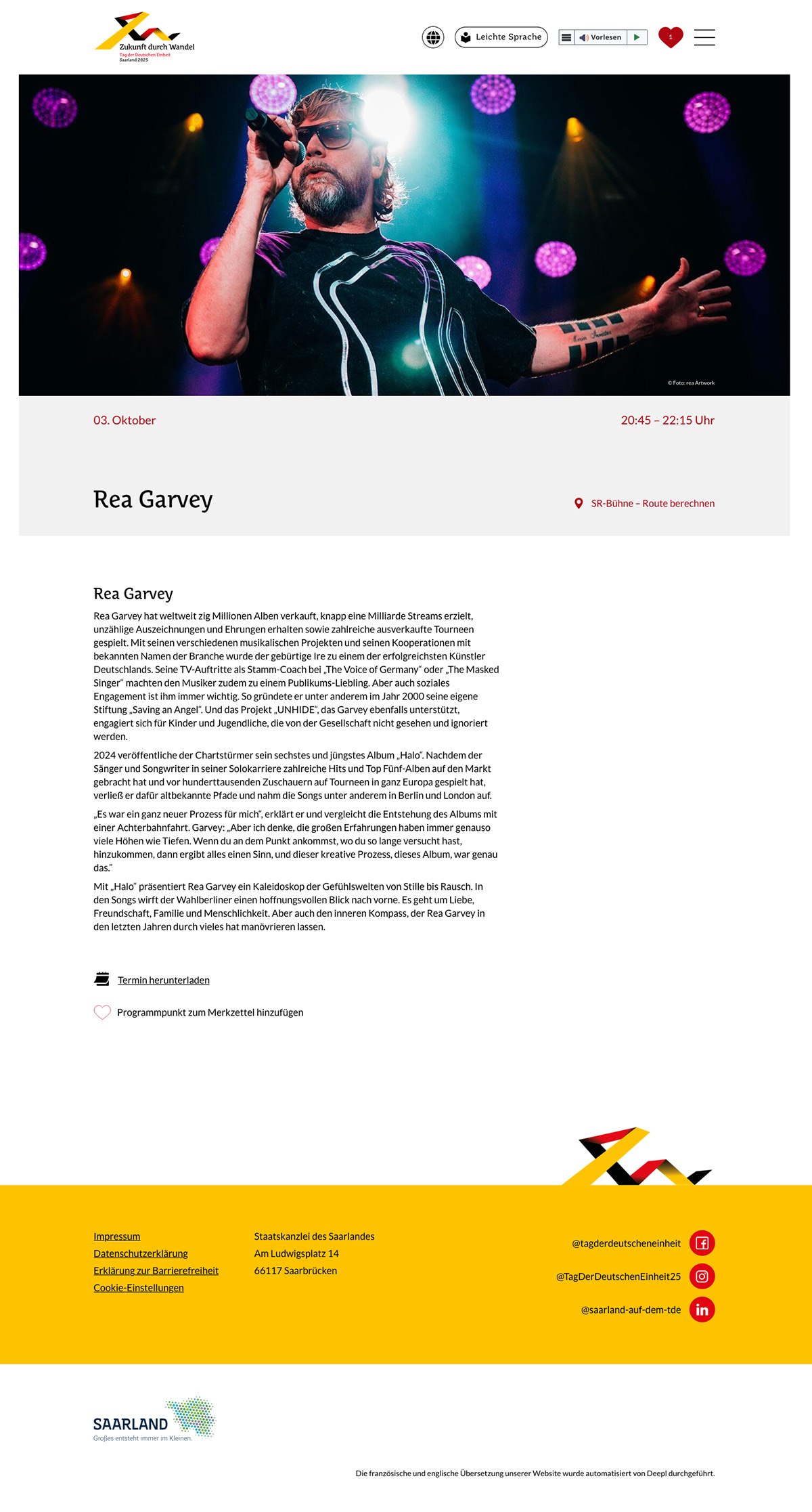 Ein bärtiger Mann, der eine Sonnenbrille und ein gemustertes T-Shirt trägt, singt auf der Bühne in ein Mikrofon, das von bunten Lichtern beleuchtet wird. Unter dem Bild werden Veranstaltungsinformationen und eine Biografie über Rea Garvey angezeigt.