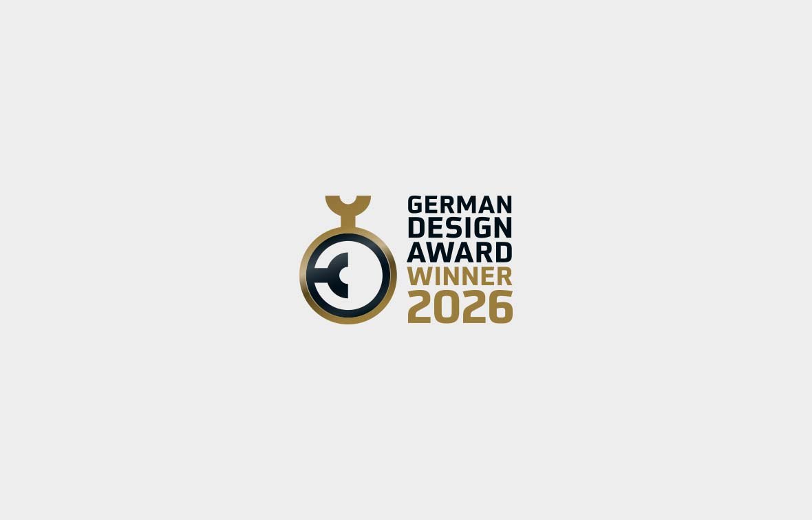 Das Logo des German Design Award Winner 2026 zeigt ein stilisiertes goldenes und schwarzes kreisförmiges Emblem links vom fettgedruckten Text, das Exzellenz und Barrierefreiheit im Design symbolisiert.