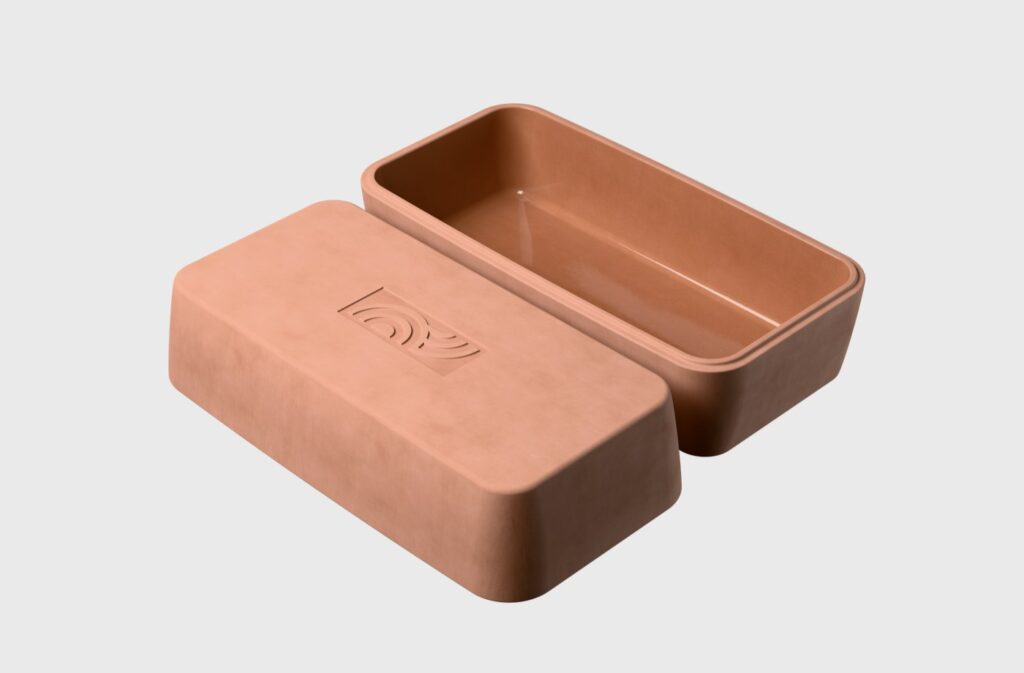 Ein rechteckiger, hellbrauner Brotkasten aus Ton mit passendem, leicht schief sitzendem Deckel und schlichtem Prägemuster - ein zeitloses Stück, das jede Event-Kampagne zum Tag der deutschen Einheit ergänzen könnte. Der Hintergrund ist einfarbig weiß.