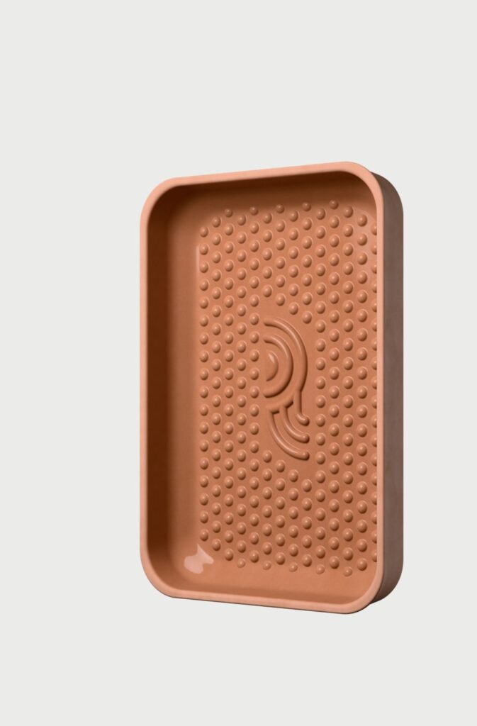 Ein rechteckiges, terrakottafarbenes Tablett mit abgerundeten Ecken, erhabenen Rändern und einer gepunkteten Textur auf dem Boden. In der Mitte befindet sich ein stilisiertes, geprägtes Design, das von der Event-Kampagne Tag der deutschen Einheit inspiriert ist.